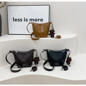 Three minimalist retro bucket bags in brown and black with plush bear charms on stands