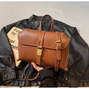 Detail of vintage brown leather handbag featuring contrast white stitching and gold hardware