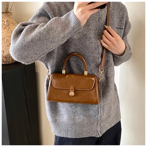 Detail of vintage dark brown leather bag with retro metal clasp and top handle