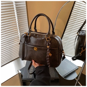 Detail of vintage dark leather boston bag featuring golden twist lock and M-logo pendant