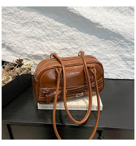 Détails du sac à main marron brillant avec anneaux argentés et décoration de nœuds