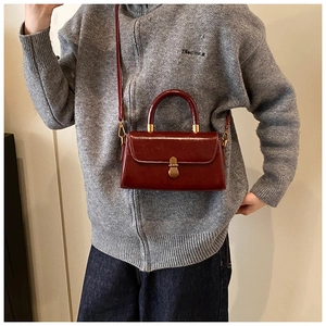 Detail of vintage burgundy leather handbag with golden metal clasp and top handle