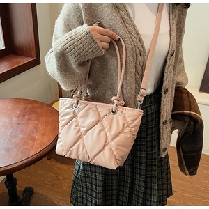 Détail du sac cabas matelassé rose clair avec boucle argentée dans un café