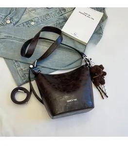 Detail of vintage bucket bag featuring crackle texture and a cute brown plush bear charm
