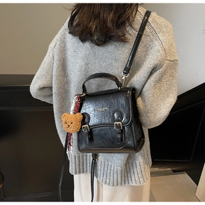 Rear view of model wearing a black retro leather square bag with a cute bear charm