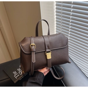 Detail of vintage brown leather bag with white stitching and gold metal buckle closure