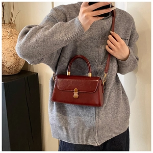 Fashionable burgundy leather crossbody bag with vintage gold clasp on female model
