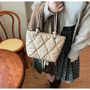 Détail du sac cabas matelassé beige avec anneaux argentés et poignées souples à nœuds