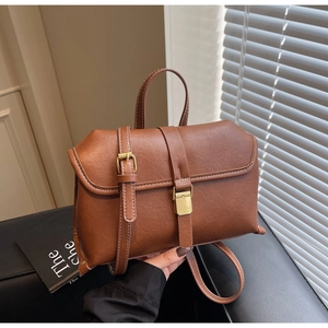 Detail of vintage brown leather bag with golden metallic buckle and lychee texture