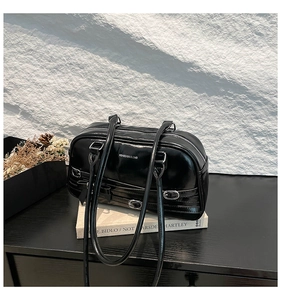Détail du sac d'épaule en cuir verni noir avec logo argenté et nœud décoratif élégant