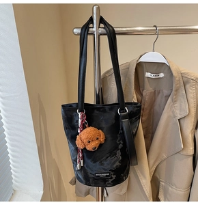 Detail of black marble-textured bucket bag with a cute plush dog charm accessory