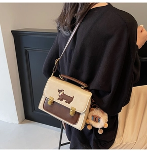 Detail view of contrast stitching small box bag with plush lion charm and dachshund patch