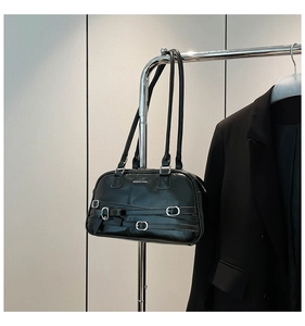 Détail du sac à bandoulière noir brillant avec boucles argentées et petit nœud