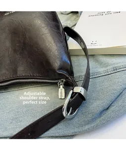 Detail view of adjustable strap and polished silver buckle on dark brown bucket bag