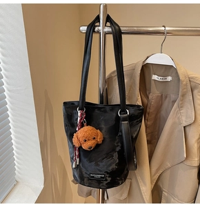 Detail of black marble textured bucket bag featuring a cute dog pendant and metal brand tag