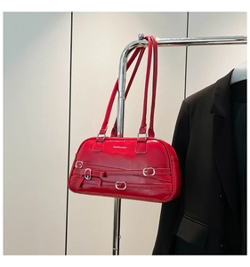 Détail du sac à bandoulière en cuir verni rouge avec boucles argentées et nœud décoratif