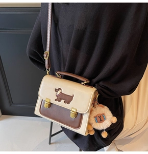 Detail of color-block crossbody bag with dachshund embroidery and plush charm accessory