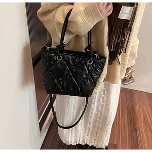 Détail d'un sac seau matelassé noir avec poignées rondes et bandoulière amovible élégante