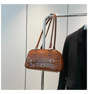 Détail macro du sac bandoulière marron avec boucle métallique et décor de nœud