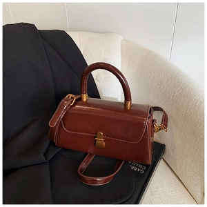 Detail of vintage brown leather handbag featuring a gold metallic lock and rounded handle