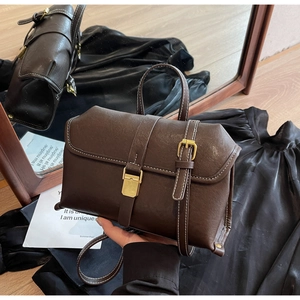 Macro shot of dark brown retro shoulder bag with white contrast stitching and gold buckles