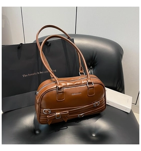 Détail du sac à bandoulière en cuir caramel avec boucles décoratives et fermeture éclair argentée
