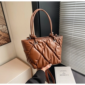 Détail d'un sac seau matelassé marron avec anneaux métalliques et bandoulière amovible