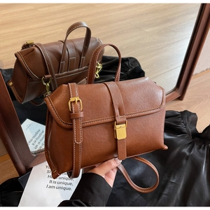 Detail of vintage brown crossbody bag with gold buckle and contrast stitching accents