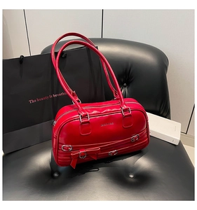 Détail d'un sac Boston en cuir verni rouge avec nœud et boucles en métal argenté