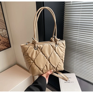 Détail d'un sac seau beige matelassé en cuir souple avec une longue bandoulière réglable