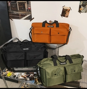 Detail view of large canvas tote bags in orange, black, and green on a display rack