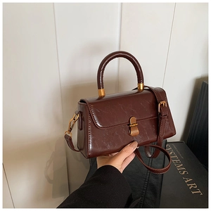 Detail of vintage brown leather bag with glossy texture and gold buckle closure