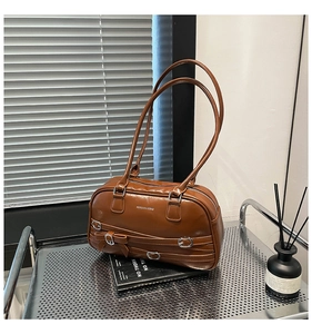 Détail de sac à bandoulière marron rétro avec boucle et décoration noeud sur étagère