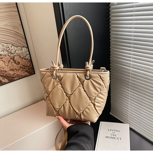 Détail d'un sac seau matelassé beige avec poignées à nœuds et bandoulière amovible