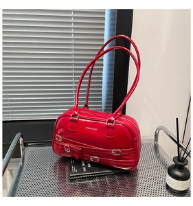 Vue détaillée du sac polochon en cuir verni rouge avec boucle argentée et nœud