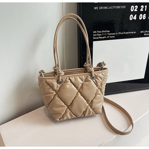 Détail du sac seau matelassé beige montrant le cuir souple et les fines bandoulières