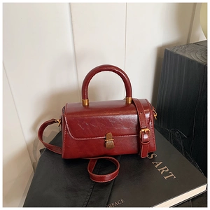 Detailed view of vintage burgundy square handbag with bronze hardware on a black book