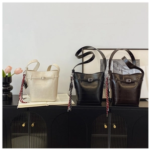 Detailed view of fashionable bucket bags in cream, black, and brown with silk scarf accents