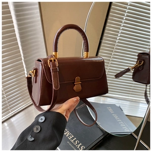 Detail of vintage brown leather square bag with gold hardware and top handle strap