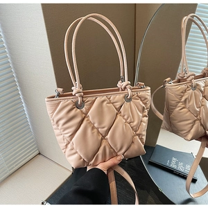 Gros plan sur le sac fourre-tout matelassé rose abricot avec poignées nouées et tissu doux