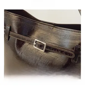 Close-up of retro dark brown bucket bag with polished oil wax leather and silver buckle