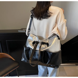 Detail of silver metallic and black leather tote bag with wide shoulder strap on model