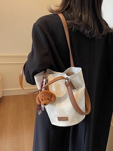 Chic white bucket bag with brown leather straps and cute puppy pendant accessory