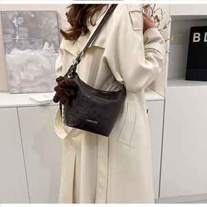 Detail of dark brown wrinkled leather hobo bag with teddy charm and silk scarf