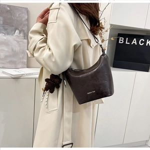 Detail of vintage dark brown bucket bag with polished leather texture and metal buckle