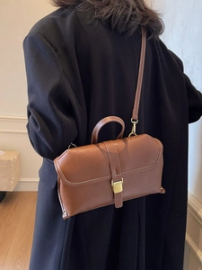 Retro brown leather crossbody bag with white stitching and gold clasp shown with model