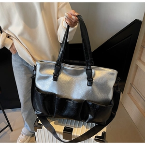 Detail of silver and black tote bag with multi-pocket texture on white suitcase