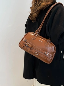 Sac à épaule en similicuir marron avec boucles et nœud porté par un mannequin