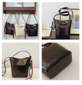 Detail of glossy bucket bags with retro texture, charm pendants, and base structure