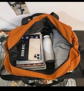 Detailed internal storage of high-capacity orange canvas tote bag with travel essentials
